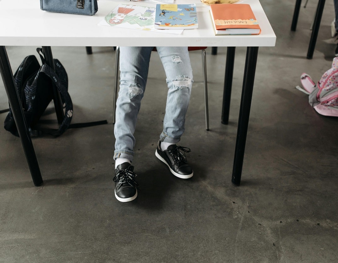 straps of students' rucksacks hanging int walkways around desks