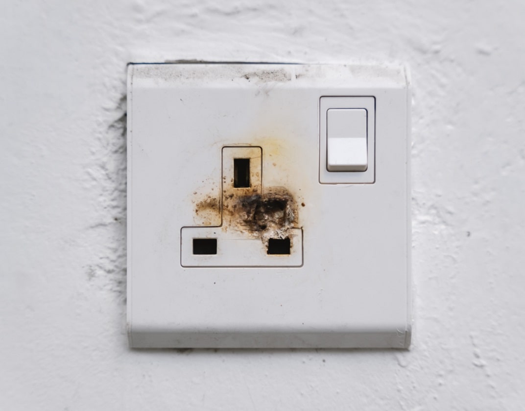 recessed single socket outlet, with brutn marks between the plug pin holes