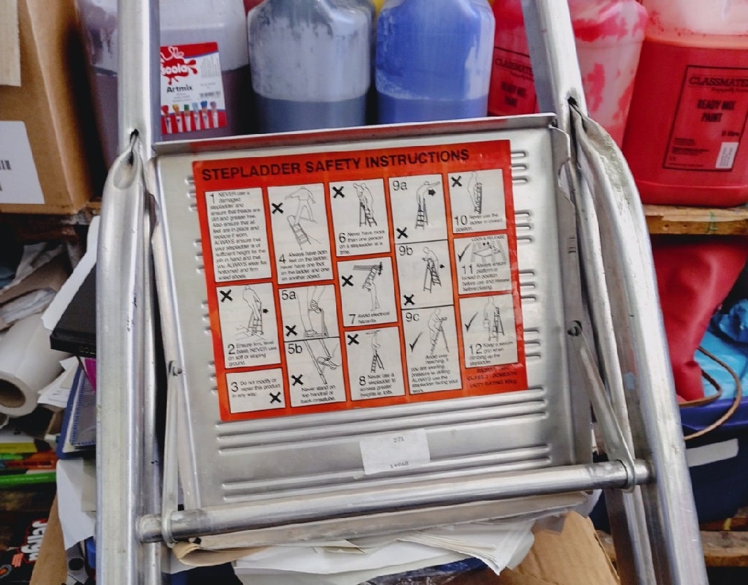 close-up of the underside of the tool-tray of a folded stepladder, showing the red label of a class 3, domestic grade stepladder