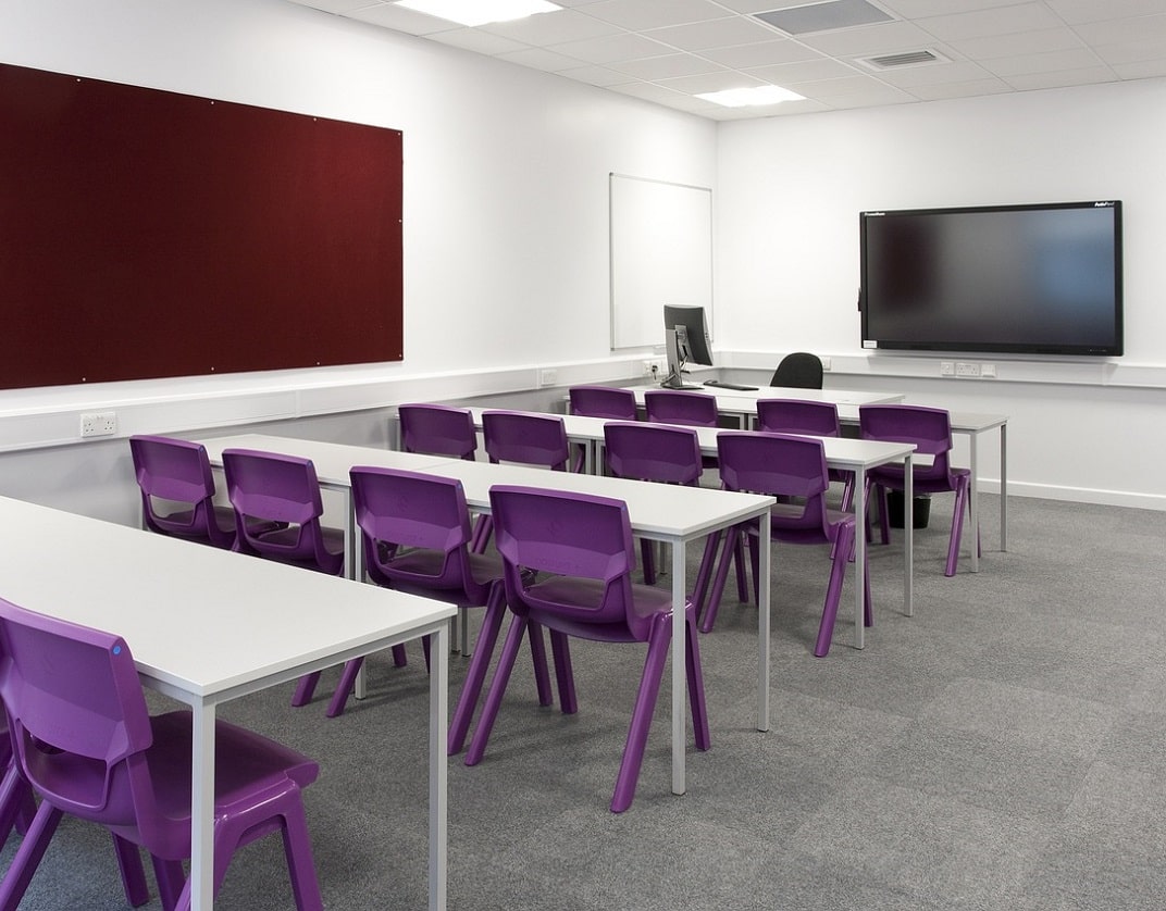 three evenly space rows of desks with a walk way on right 