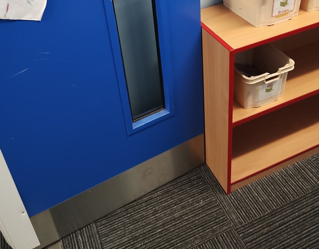 storgage cupboard being used to hold open blue fire door