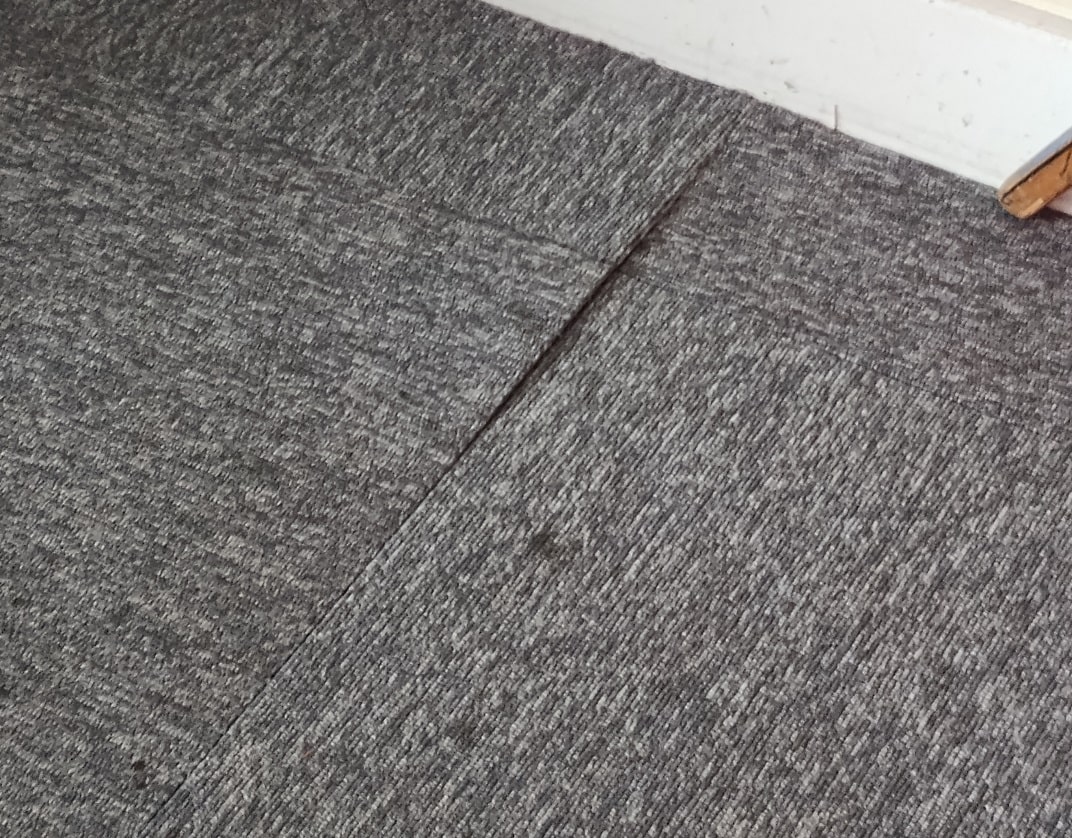 grey carpet tiles lifting where two tiles meet