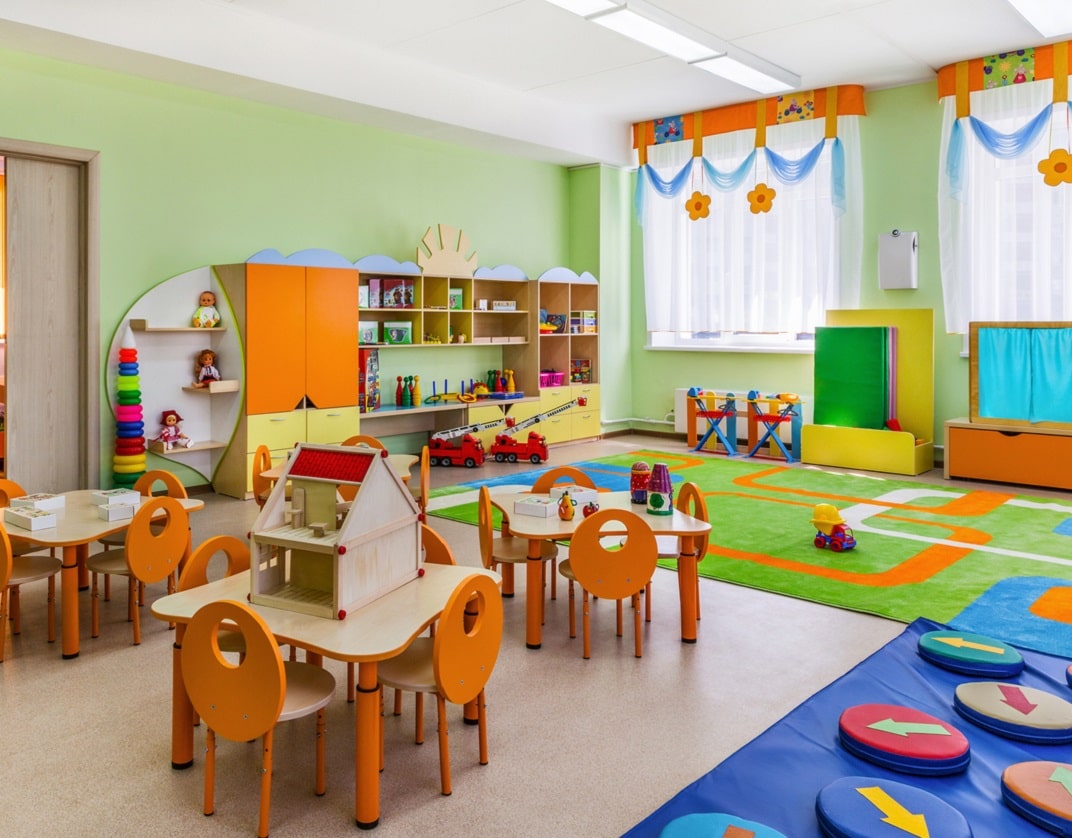 nursery classroom with a vinyl floor covering with large playmats near tables and chairs