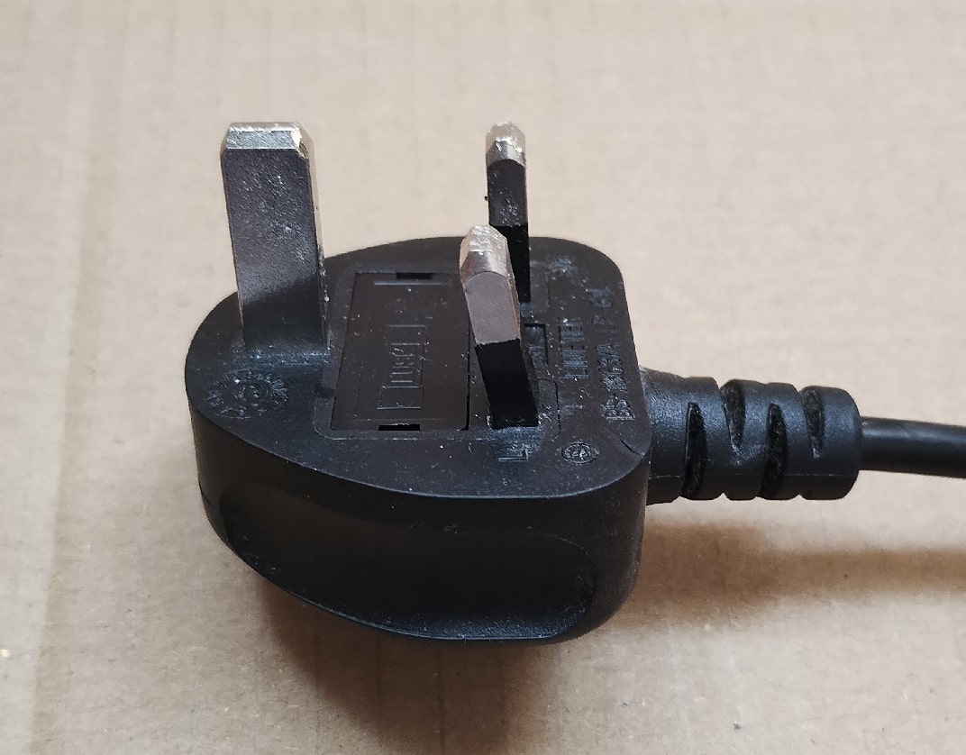 close-up of black moulded UK-style plug with a bent conductor pin