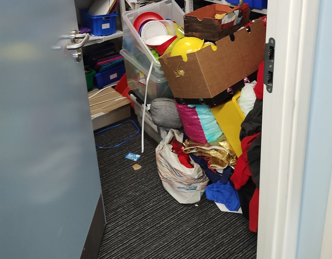 view into a walk-in storage cupboard with items stacked precariously