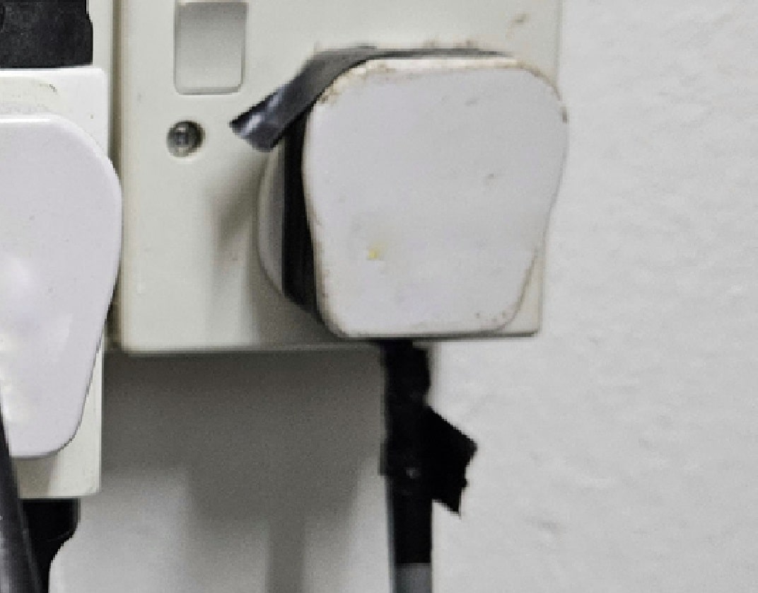 plastic UK-style plug which has had black insulating tape wound around the the join in the two halves of the plug and on the flex entering the plug casing