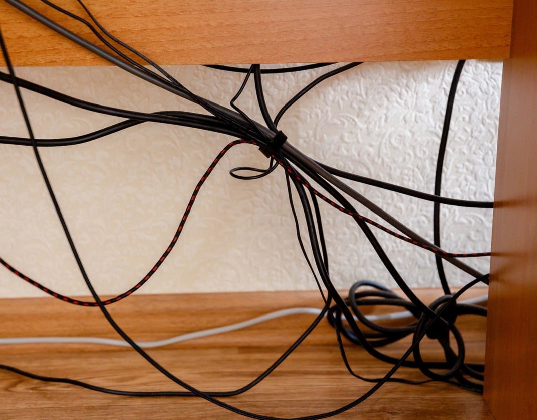 a tangle of trailing leads under a desk