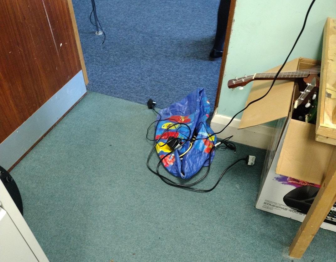 view from inside a walk-in storage cupboard of electrical leads and coloured plastic bag obstructing about 50% of the doorway