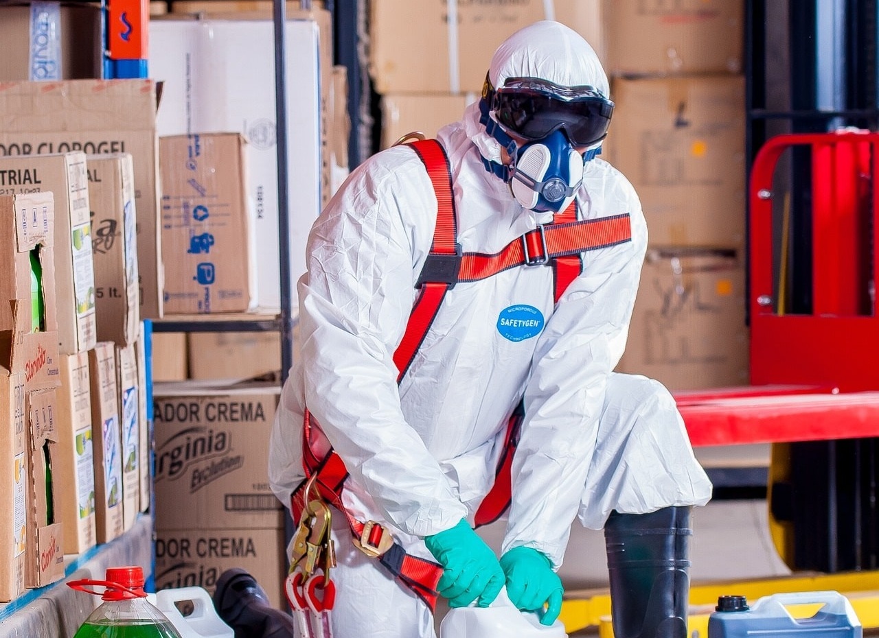a person wearing proective overall, gloves, eye proection and half-mask respirator